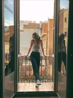 a woman standing on a balcony looking out the window