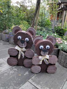 two teddy bears made out of wood sitting next to each other in front of flowers