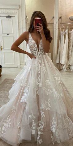 a woman taking a selfie in a wedding dress with white flowers on the skirt