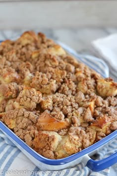 a casserole dish with apples and crumbled toppings sitting on a striped cloth