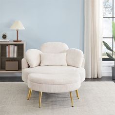 a living room with a white chair and a large round ottoman in front of a blue wall