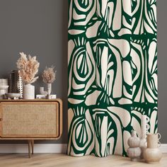 a green and white shower curtain next to a wooden cabinet with vases on it