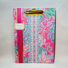 a pink and blue floral clipboard with gold trimmings on the side, sitting against a white background