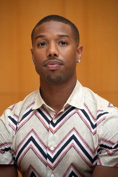 a man in a chevron shirt looks at the camera with an intense look on his face