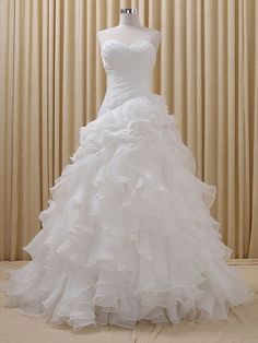 a white wedding dress on a mannequin in front of a curtained wall