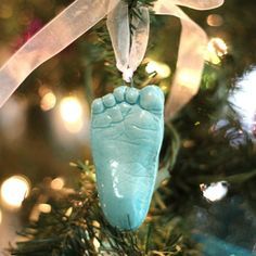 an ornament hanging from a christmas tree with the foot of a baby's feet