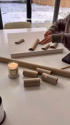 a woman sitting at a table working on some kind of crafting project with candles