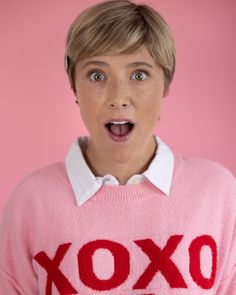 a woman in a pink sweater making a surprised face