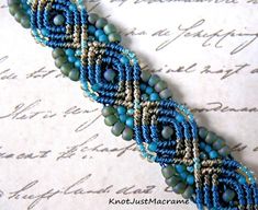 a blue and beige beaded bracelet sitting on top of a piece of paper