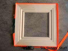 an orange and white frame sitting on top of a gray floor next to a pair of scissors