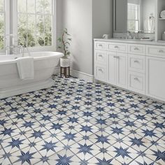 a bathroom with blue and white tiles on the floor, sink, tub and mirror