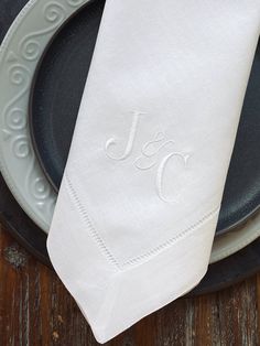 the monogrammed napkin is on top of an empty plate with a black rim