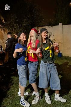 three young women standing next to each other on top of a grass covered field at night