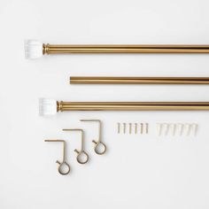 three brass and white brushes are on the table next to some metal scissors, wire, and hooks