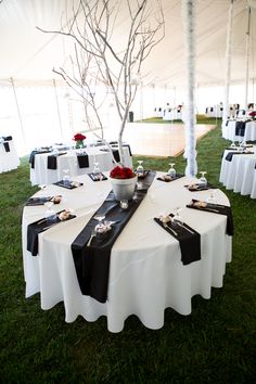 a table set up with black and white linens for an outdoor wedding or reception