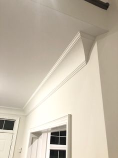 the corner of a room with white walls and trimmings on the ceiling is shown