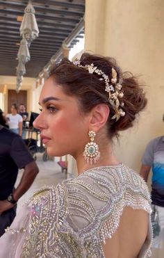 a woman in a white dress with some jewelry on her head