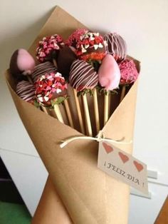 chocolate covered strawberries are wrapped in brown paper and tied with twine to a wooden stick