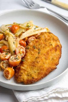 a white plate topped with meat, pasta and veggies next to a fork