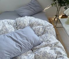 an unmade bed with blue and white comforter in a small room next to a mirror