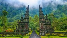 an image of a gated entrance to a lush green park with mountains in the background