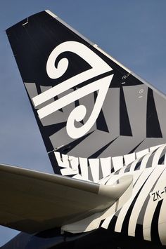 the tail end of an airplane that is painted black, white and grey with designs on it