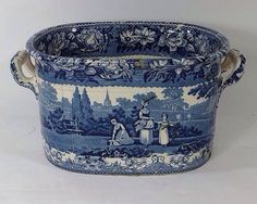 a large blue and white basket with handles on the rim, decorated with women in a garden scene