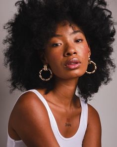 a close up of a person with an afro hair style and wearing a white tank top