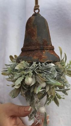 a bell hanging from a metal pole with flowers and leaves on it's side