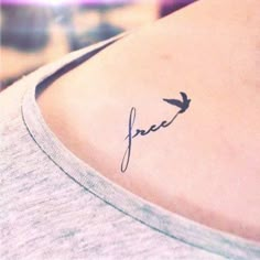 a small tattoo on the back of a woman's shoulder that reads, free