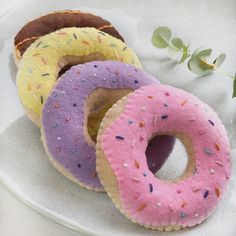 three donuts with sprinkles are sitting on a plate next to a plant