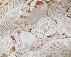 white lace with flowers and leaves is shown on a tablecloth, close - up