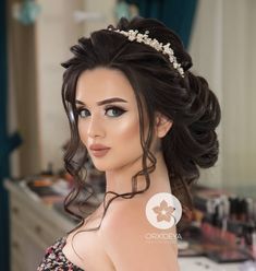 a woman with long hair wearing a tiara in a dressing room looking at the camera