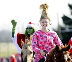 two people in costumes riding horses with grinen on their backs and one person wearing santa's hat