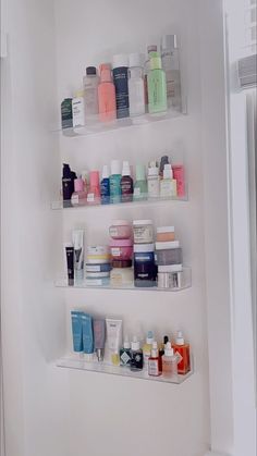 shelves filled with different types of skin care products in a white walled bathroom area next to a window