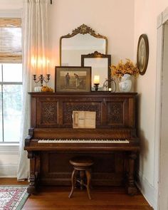 an old piano sitting in the corner of a room next to a mirror and window