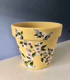 a yellow flower pot with white flowers painted on it