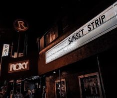 people walking on the sidewalk at night in front of roxy theater and sunset strip sign