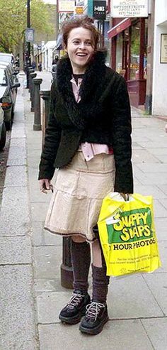 a woman is standing on the sidewalk with a shopping bag in her hand and smiling