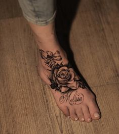 a woman's foot with a rose tattoo and name written on the bottom of it