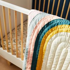 a crib with four pillows on top of it and a blanket hanging from the rails