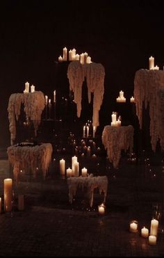 many candles are lit on the ground in front of some rocks and trees with icicles