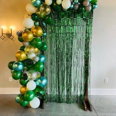 green and gold balloon arch with streamers for an entrance to a party or event