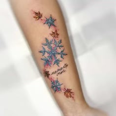 a snowflake tattoo on the arm with words written in blue and red ink