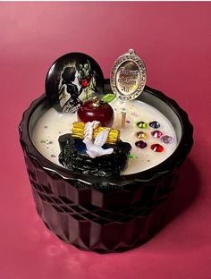 a heart shaped container filled with lots of candy and candies on top of a pink surface