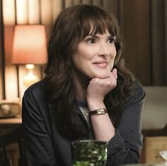 a woman sitting at a table with a glass in front of her and looking to the side