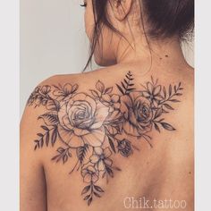 a woman's back tattoo with flowers and leaves