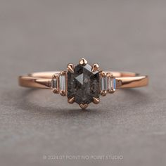 a close up view of a ring with a black diamond and three baguets