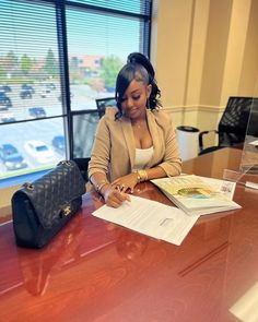 a woman sitting at a desk signing papers