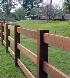 a wooden fence in the middle of a grassy field